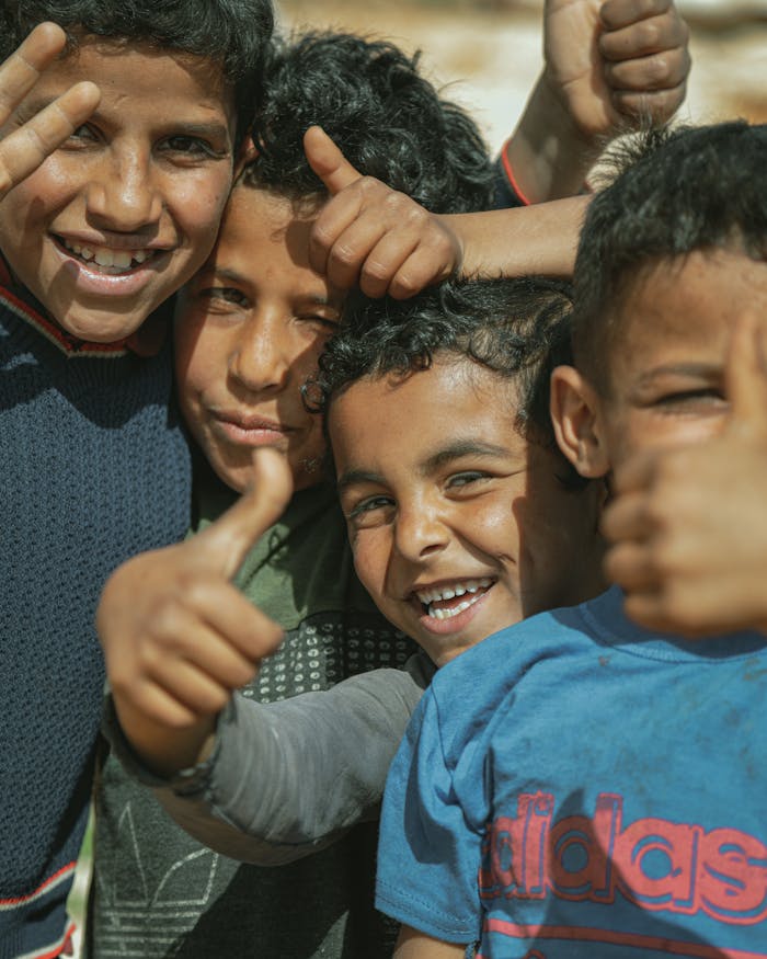 A joyful group of boys smiling and showing thumbs up in Idlib, Syria.