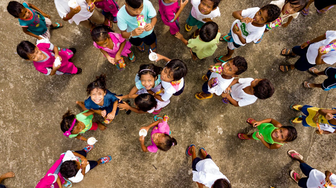 A vibrant top view of cheerful children gathered on pavement, smiling and socializing.